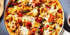 a casserole dish with tomatoes, spinach and cheese in it on a blue surface