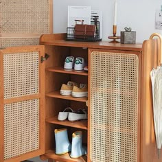 an open cabinet with shoes and umbrellas on the top shelf in front of it