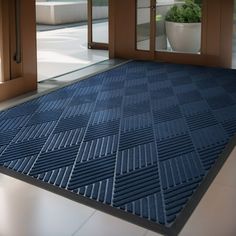 a blue door mat is on the floor in front of an open glass door and potted plant