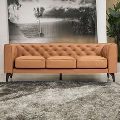 a tan leather couch sitting in front of a painting