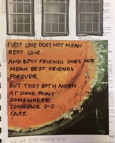 an orange piece of paper with words written on it in front of two windows and a tree trunk