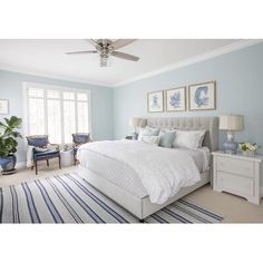 a bedroom with blue walls and white bedding in the center is decorated with striped rugs