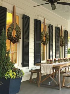 a screen shot of a porch with black shutters and potted plants on it