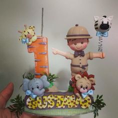 a person holding up a cake shaped like a boy with animals on it's side