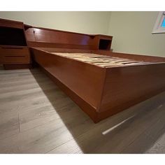 a wooden bed frame sitting on top of a hard wood floor next to a window