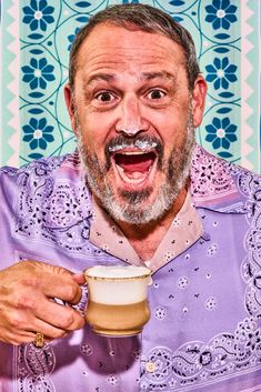 an older man holding a cup of coffee and making a funny face with his mouth wide open