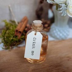 an empty bottle with a tag on it sitting on a table next to some flowers