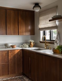 a kitchen with wooden cabinets and white counter tops, along with a rug on the floor