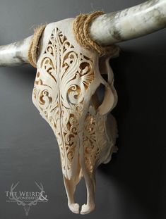 an animal's skull is carved from wood and has intricate carvings on the horns