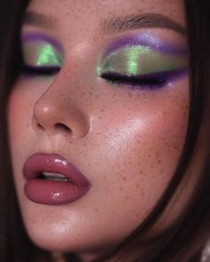 a close up of a woman with green and purple eyeshades on her face