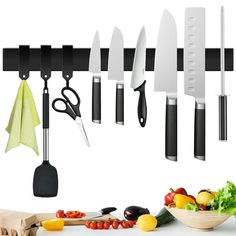 the kitchen utensils are hanging on the wall above the cutting board and vegetables