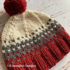 a red and gray knitted hat with a pom - pom on top