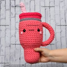 a hand holding a pink crocheted coffee cup