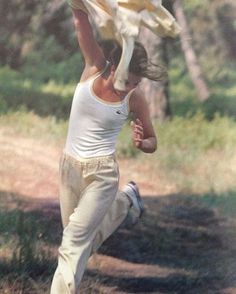 a woman jumping up in the air to catch a frisbee with her hands