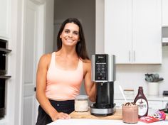 a woman standing in front of a coffee maker with ingredients on the kitchen counter top