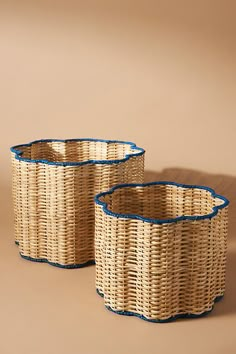 two woven baskets with blue trims on the sides, sitting side by side in front of a beige background