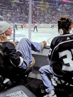 two people sitting in chairs watching an ice hockey game