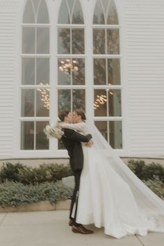 a bride and groom kissing in front of a church