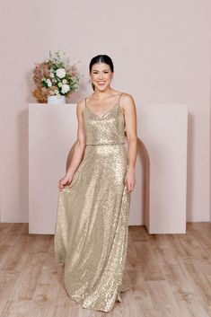 a woman in a gold dress standing on a wooden floor