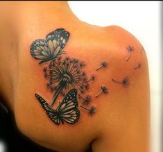 the back of a woman's shoulder with two butterflies on it and dandelions