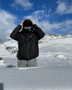 a man standing on top of a snow covered slope holding his hands to his head