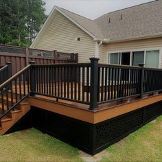 a wooden deck with black railings in front of a house