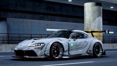 a white sports car driving down a street next to a tall building with lights on