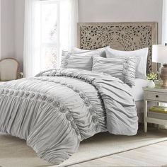 the comforter is made up with ruffled sheets and white bedding, along with two nightstands