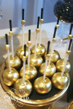 there are many gold candies in the bowl on the table with black and white sticks sticking out of them