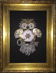 an owl made out of glass and beads in a gold frame with a key hanging from it's side