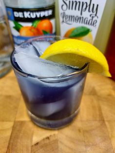 a blue drink with ice and lemon wedges