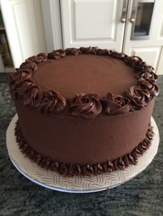 a chocolate cake sitting on top of a counter next to a white plate with brown frosting