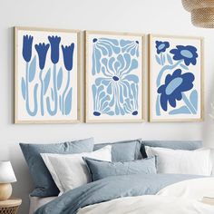 two blue and white paintings on the wall above a bed