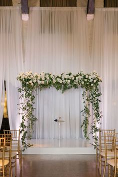 an indoor ceremony with white flowers and greenery