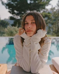 a woman sitting at a table next to a pool