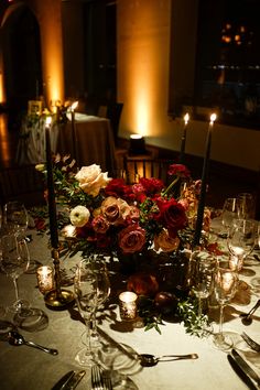 the table is set with candles, flowers and wine glasses for an elegant wedding reception