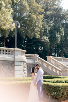 a bride and groom standing in front of some bushes