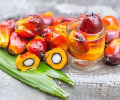 some fruit is sitting on a leaf next to a glass with something red and yellow in it