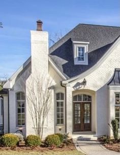 a white house with black shutters and two story windows on the front door is shown