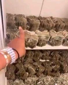 a hand reaching for a can of beer in front of stacks of money