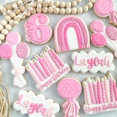 pink and white decorated birthday cookies on a table with balloons, streamers, candles, and other decorations