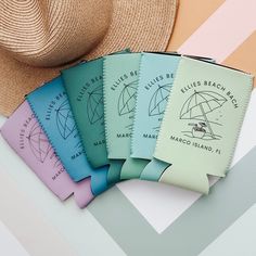 five different colored passports sitting next to a straw hat on top of a table