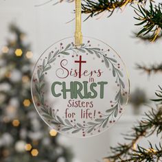 a glass ornament hanging from a christmas tree with the words sisters in christ