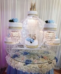 a table topped with three tiered cakes covered in white frosting and blue flowers