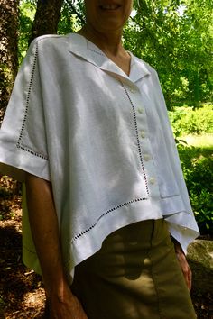 an older woman wearing a white shirt and green skirt standing in front of a tree