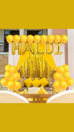 yellow balloons and streamers decorate the entrance to an event with gold foil letters on it