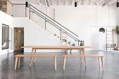 an empty room with two benches and a table in front of the stair railings