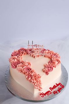 a heart shaped cake with pink frosting on top