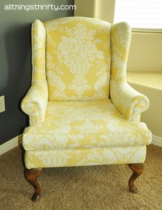 a yellow chair sitting on top of a carpeted floor in front of a window