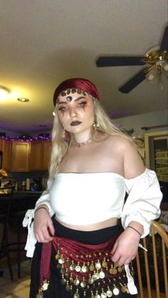 a woman in a white top and black skirt with gold chains on her waist is posing for the camera